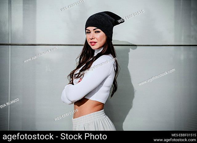 Confident woman with arms crossed standing against wall
