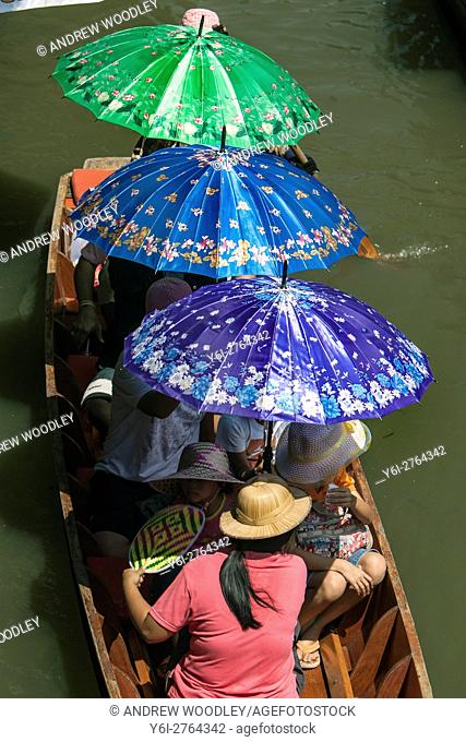 Tourists with coloured parasols floating market Damnoen Saduak outside Bangkok Thailand