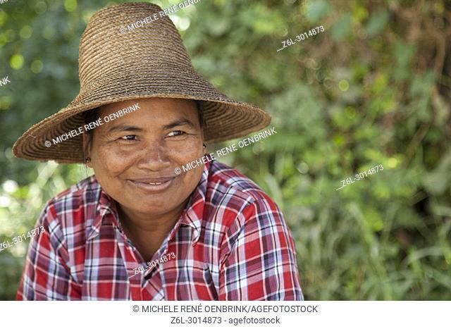 local Burmese woman with straw hat on selling local crops in Myanmar