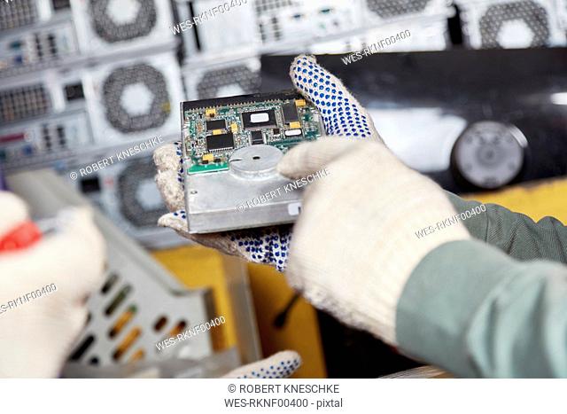 Worker holding hard disk in computer recycling plant