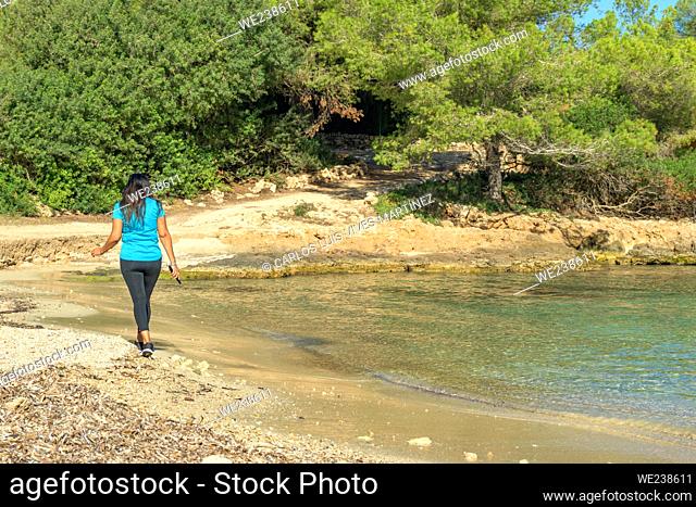 Latina sportswoman, walking along the shore of a Mediterranean island beach,