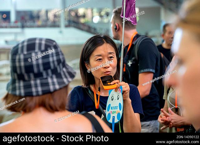 Xian, China - July 2019 : China female tour guide talking to a mobile device so her group can hear her while visiting a museum, Xian, Shaanxi Province