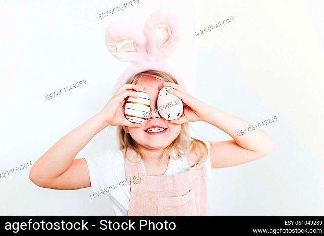 Little girl with Easter eggs and bunny ears hat. High quality photo