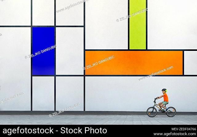 Boy riding BMX bike by colorful patterned wall