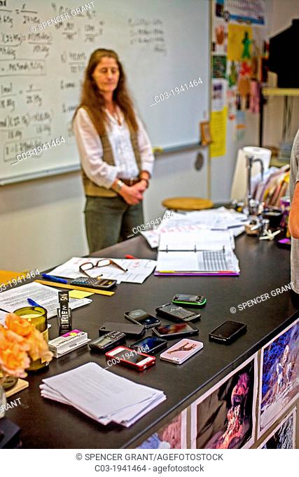 A high school chemistry teacher conducts her class with the students' cell phones stacked on her desk in San Clemente, CA, in an example of classroom management