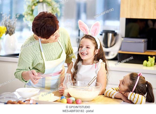 Grandmother and granddaughters baking Easter cookies in kitchen together