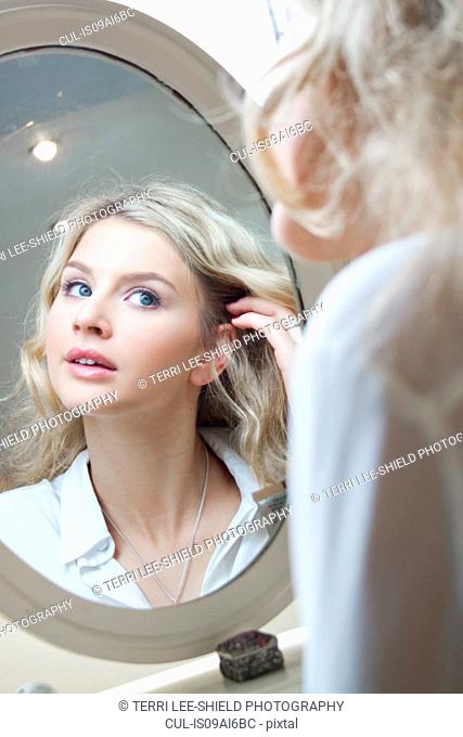 Teenage girl looking in mirror, doing her hair