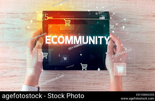 Close-up of a hand holding tablet with ECOMMUNITY inscription, online shopping concept