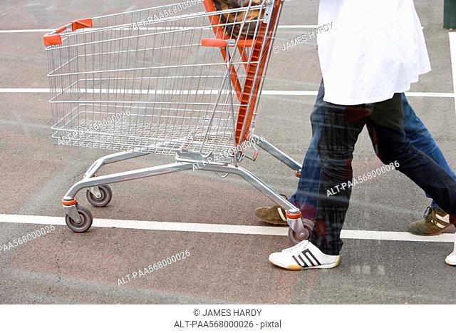 Empty shopping cart being pushed across parking lot