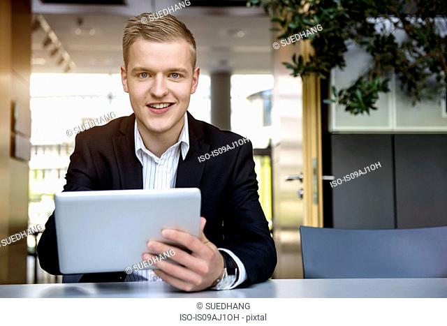 Portrait of young man in office using touchscreen on digital tablet