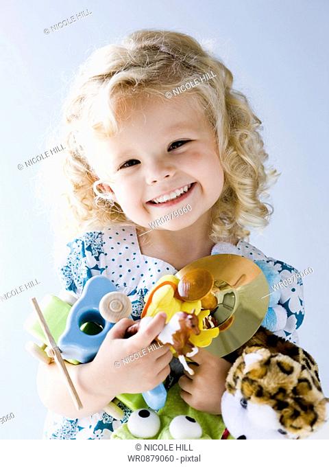 little girl holding an armful of her toys