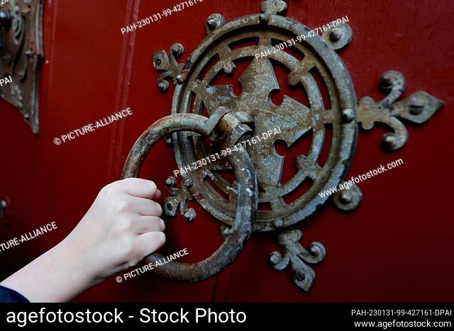 PRODUCTION - 31 January 2023, Saxony-Anhalt, Wernigerode: One hand grasps the door handle to the tower ascent of the castle