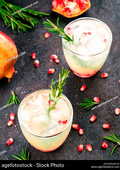 Autumn and winter cocktails idea - white sangria with rosemary, pomegrante and lemon juice and ingredients on black cement background