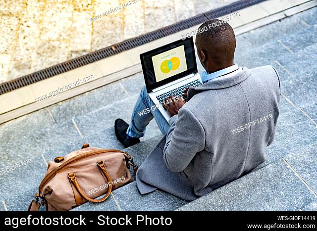 Businessman planning strategy using laptop sitting on steps