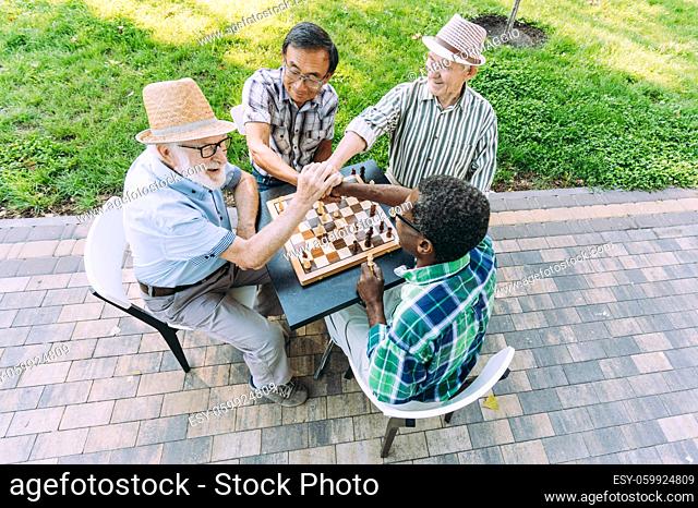 Group of senior friends playing chess game at the park. Lifestyle concepts about seniority and third age