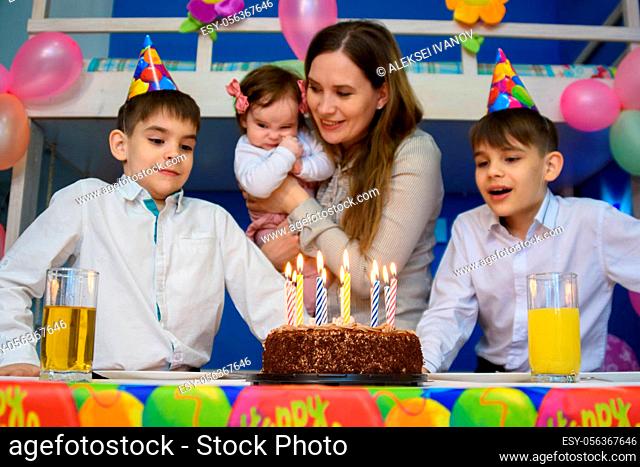 Children prepare to put out candles on a festive cake