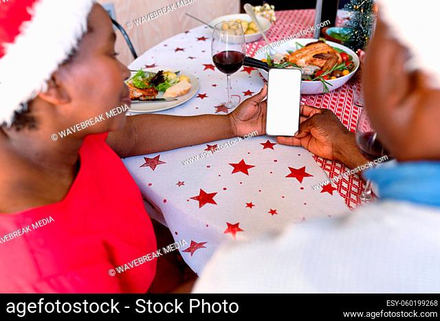 Hands of fafrican american senior couple using smartphone with copy space at christmas time