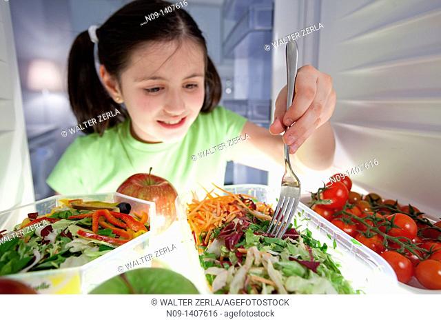 Girl eats salad from the fridge