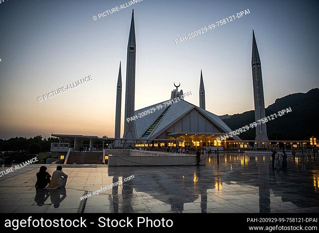 29 September 2020, Pakistan, Islamabad: Visitors to the Faisal Mosque in the Pakistani capital Islamabad sit on the forecourt of the mosque at sunset