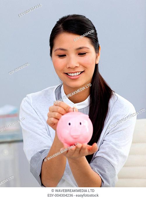 Asserive businesswoman saving money in a piggybank
