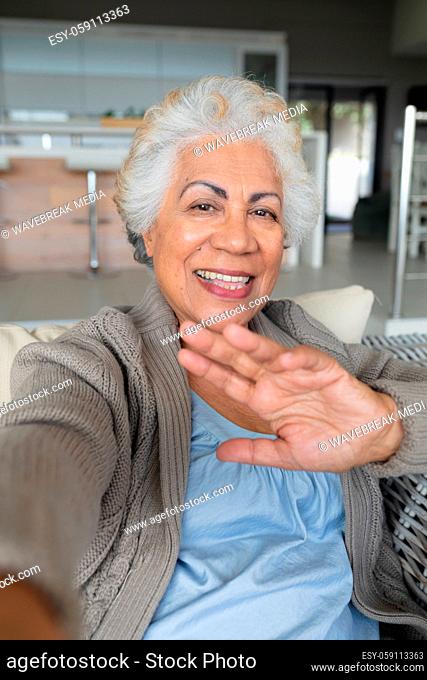 Portrait of mixed race senior woman sitting on sofa making video call