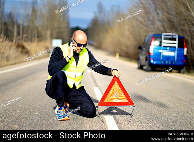 Man using a smartphone having a car breakdown