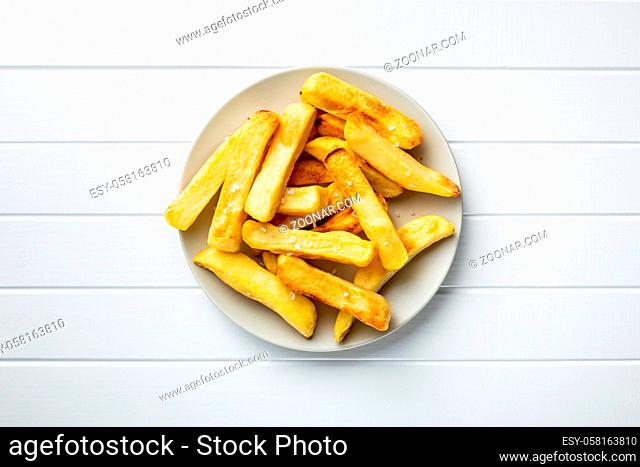 Big french fries. Fried potato chips on plate. Top view
