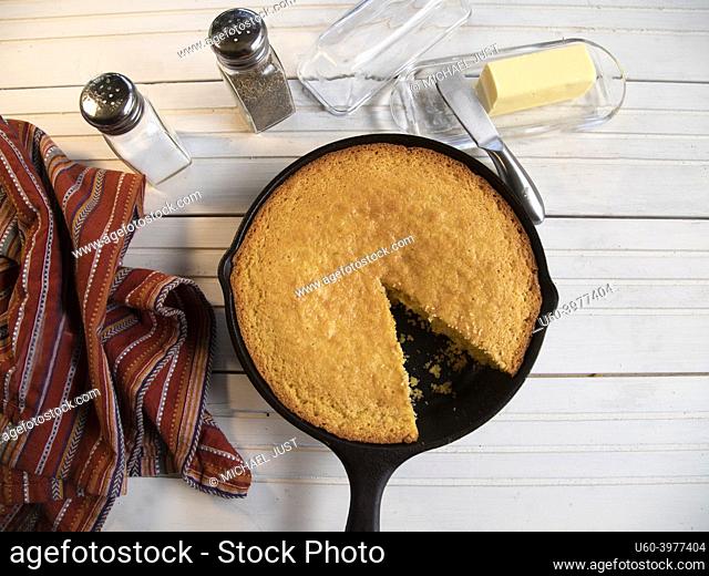 Cornbread in cast-iron skillet top view on white wood table
