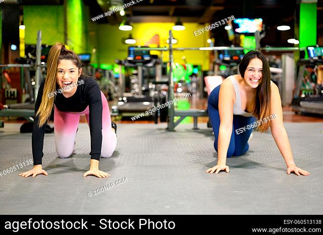 Two young women doing high planks in gym. High quality photo