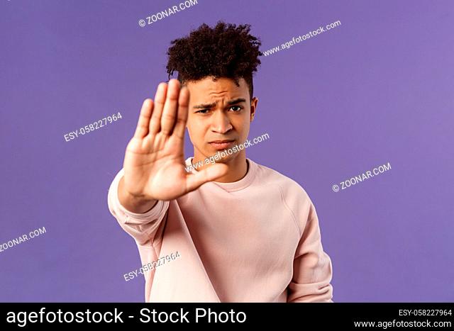Man you should stop. Close-up portrait of young serious-looking male friend trying to warn person of doing something bad, raise hand to prohibit