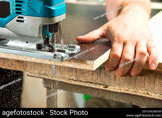 Close-up a carpenter saws an electric jigsaw piece of wood