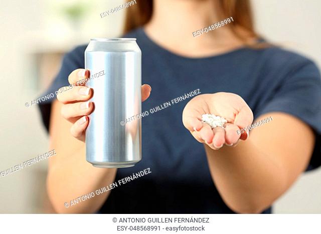 Front view close up of a woman hands holding a soda drink can and saccharin at home