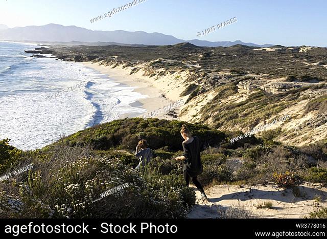 A teenager and her brother on a path down to a sandy beach