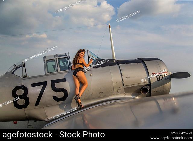 A brunette model in vintage clothing a WW II aircraft