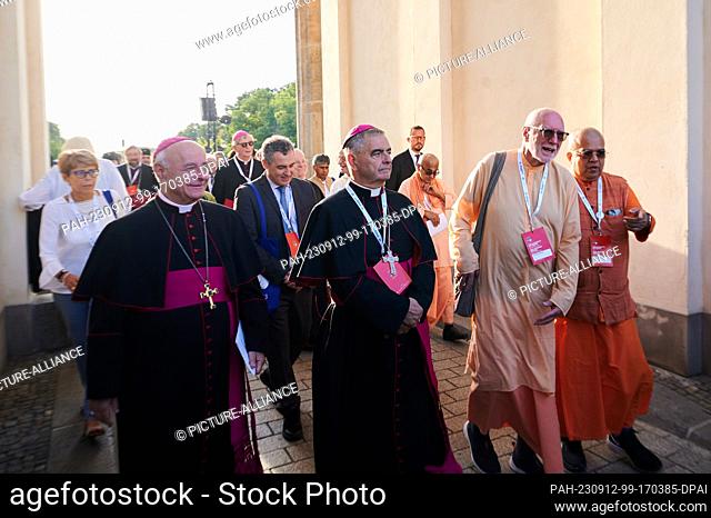 12 September 2023, Berlin: Clergymen from different world religions walk through the Brandenburg Gate during the closing rally of the International Meeting of...