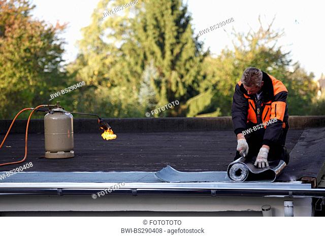 man laying on tar paper on a garage, Germany