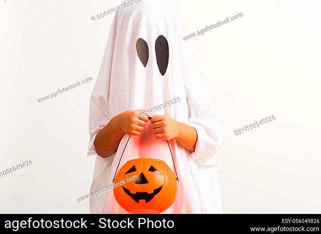Funny Halloween Kid Concept, little cute child with white dressed costume halloween ghost scary he holding orange pumpkin ghost on hand
