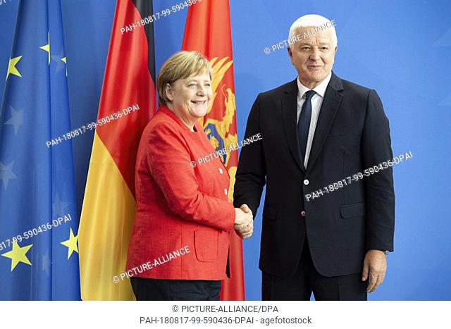 17 August 2018, Germany, Berlin: Federal Chancellor Angela Merkel (CDU) shakes hands with Dusko Markovic, Prime Minister of Montenegro