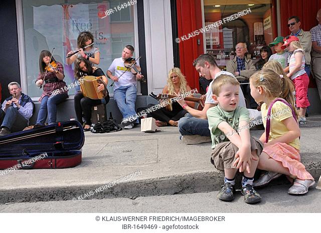 Making music with a violin, an accordion, a guitar and a flute at an Irish music session in the street, music festival Fleadh Cheoil na hEireann in Tullamore