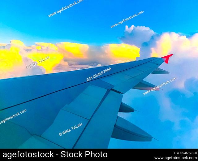View from an airplane on a blue sky and white clouds. Flying on the airplane. Wing of airplane flying above the clouds in the sky. Oval window window