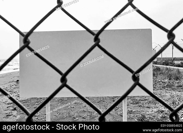 Blank danger or warning sign through wire mesh fence - space for your own text. Blaclk and white image