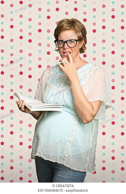 Confused young pregnant woman on polka dot background