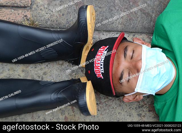 A university activist wears mask lying on the floor with black boots on his head, during the performance carried out in the Plaza de Bolivar by university...