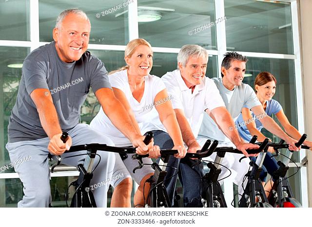 Zufriedene Senioren trainieren im Spinning-Kurs im Fitnessstudio
