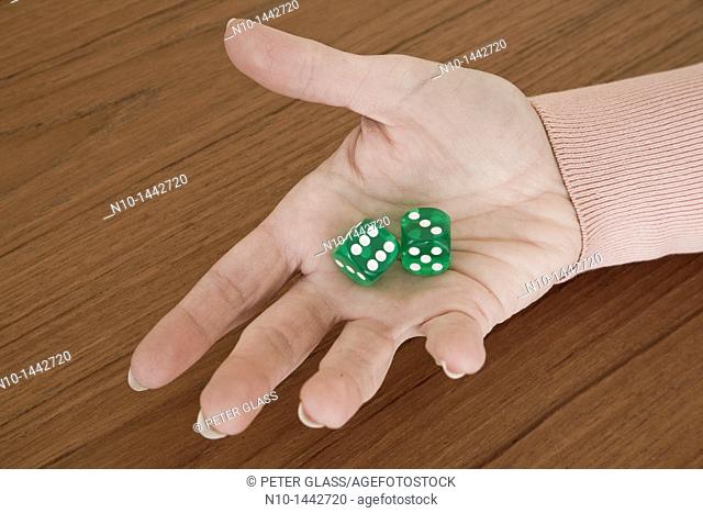 Young woman's hand holding a pair of green dice