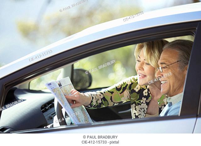 Senior couple looking at map inside car