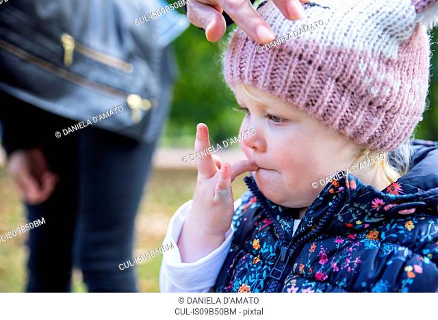 Female toddler with finger in her mouth in park