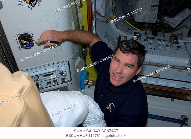 Astronaut Steve Bowen, STS-126 mission specialist, signs Endeavour's crew patch in the Quest Airlock of the International Space Station on Thanksgiving Day