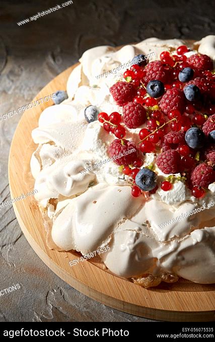 pavlova meringue cake with berries on wooden board