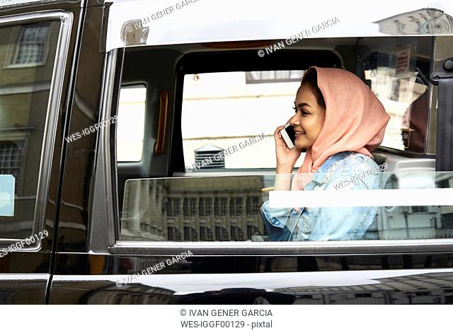 UK, England, London, young woman wearing hijab on the phone in a taxi